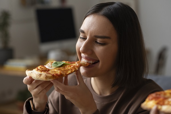 Ragazza mangia una fetta di pizza.
